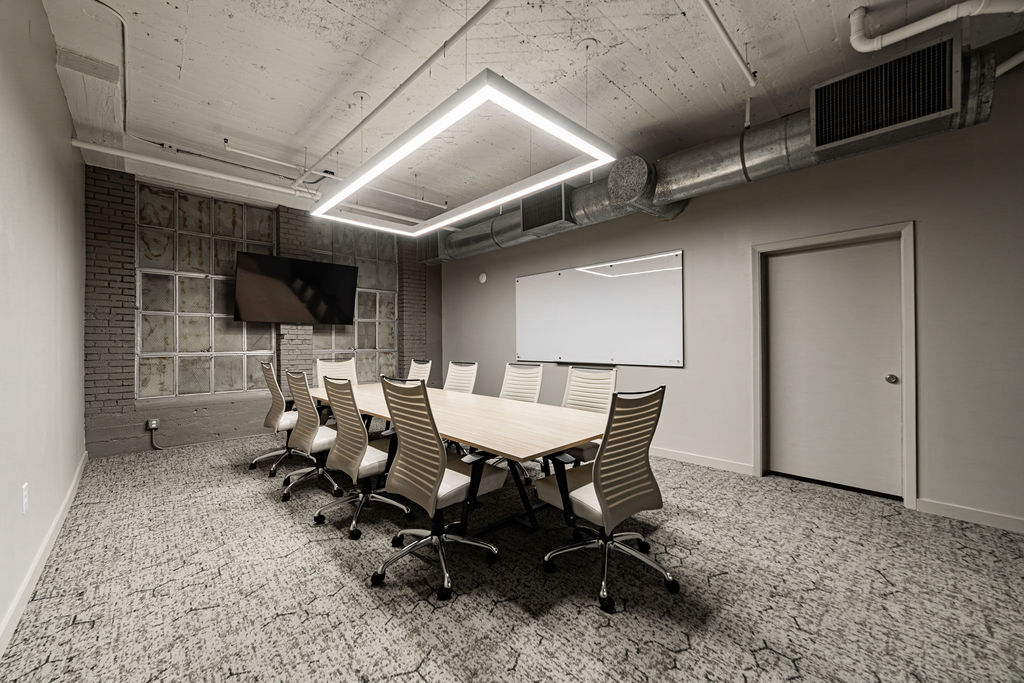 Ten-person boardroom with conference table, TV, and whiteboard at The District at Hogg Palace downtown Houston